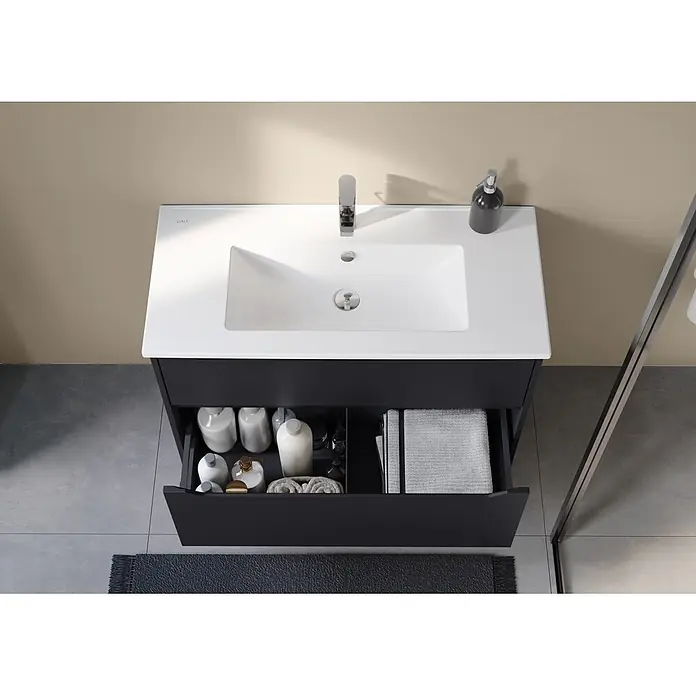 VitrA Integra Square Badmöbel-Set - Gesamtbreite Badmöbel: 100 cm, Graphit, Matt - Schwarzer Badunterschrank mit integriertem weißen Waschbecken, Chromarmatur und offener Schublade mit Flaschen und Handtüchern in einem modernen Bad.