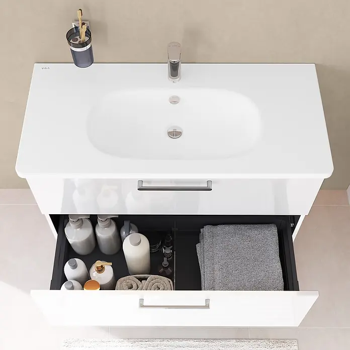 VitrA Badmöbel-Set Root Flat - B x T x H: 80 x 45 x 65 cm, Weiß, Hochglänzend - Weißer Waschtischunterschrank mit integriertem Waschbecken und zwei geöffneten Schubladen, die Pflegeprodukte und Handtücher zeigen.