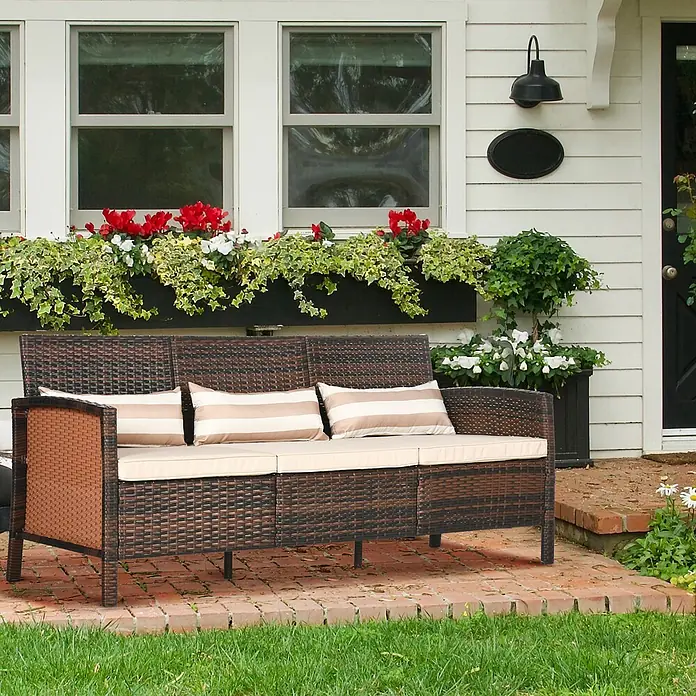 Outsunny Gartenstuhl-Set Outdoor-Sitzecke 3-teilig - 3 Stk., Stahl, PE-Kunststoff, Polyester - Dunkelbraunes Rattan-Outdoor-Sofa mit beigefarbenen Kissen und gestreiften Polstern auf einer Backstein-Terrasse.