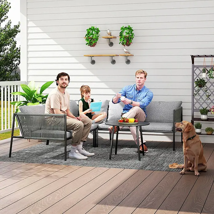 Outsunny Gartenstuhl-Set Polyrattan Lounge-Set -  - Graues Outdoor-Sofa-Set und schwarzer Couchtisch auf einer Terrasse, von einer Familie und einem Hund genutzt.