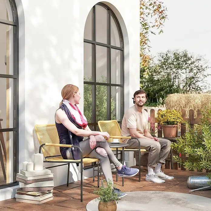 Outsunny Gartenstuhl-Set mit Tisch - 2 Stk., Stahl, PE-Rattan, Grau, Braun, B x T x H: 54 x 66 x 76 cm - Zwei gelb geflochtene Gartenstühle mit dunklen Gestellen und passendem Beistelltisch auf einer Terrasse, von Personen genutzt.
