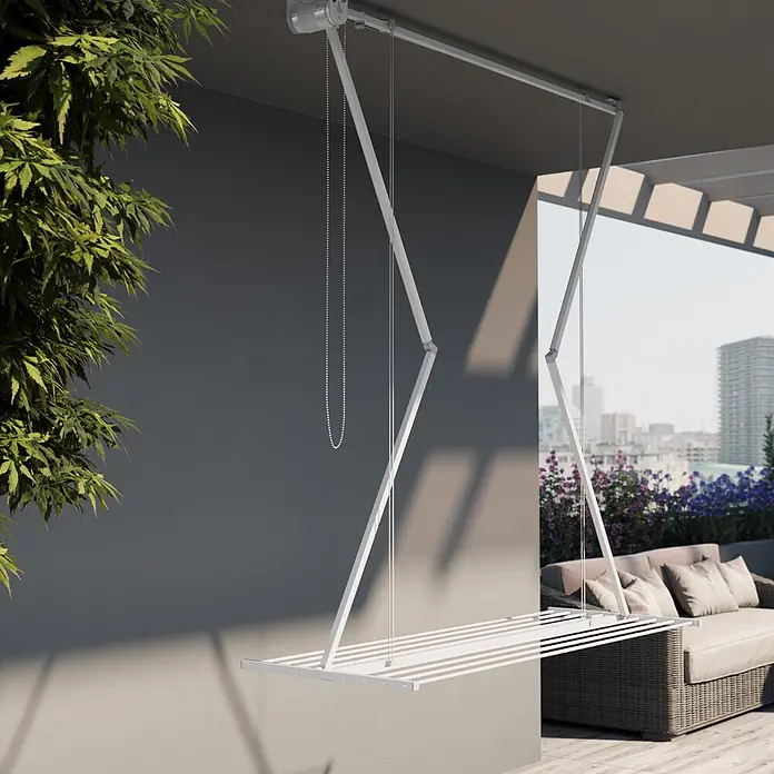 Foxydry Deckenwäschetrockner Mini 120 Weiß - L x B: 54 x 128 cm, Weiß - Weißer Deckenwäscheständer, ausgefahren auf einem modernen Balkon mit Stadtblick, Pflanzen und Gartenmöbeln.