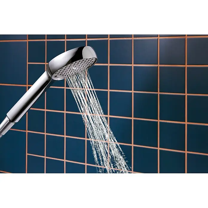 Hansgrohe Teleducha Activera Select S - Diámetro: 9,5 cm, Cromo - Un cabezal de ducha cromado rocía agua sobre una pared de azulejos oscuros.