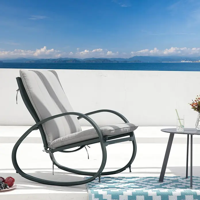 SVITA Garten-Schaukelstuhl EIBY DELUXE - 1 Stk., 50 % Polyester, 50 % Stahl, Hellgrau, B x T x H: 65 x 88 x 87 cm - Dunkelgrauer Outdoor-Schaukelstuhl mit hellgrauen gestreiften Kissen auf einer Terrasse mit Meerblick.