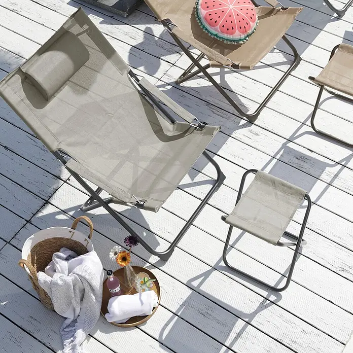 SVITA Garten-Liegestuhl TOMRA mit Hocker - 1 Stk., Pulverbeschichteter Stahl, Kunststoffgewebe, Klappbar, Hellgrau, B x T x H: 61 x 77 x 93 cm - Faltbare Outdoor-Sitzgelegenheiten: ein grauer Liegestuhl, beiger Klappstuhl und Hocker auf einer Holzterrasse mit Handtüchern und Getränken.