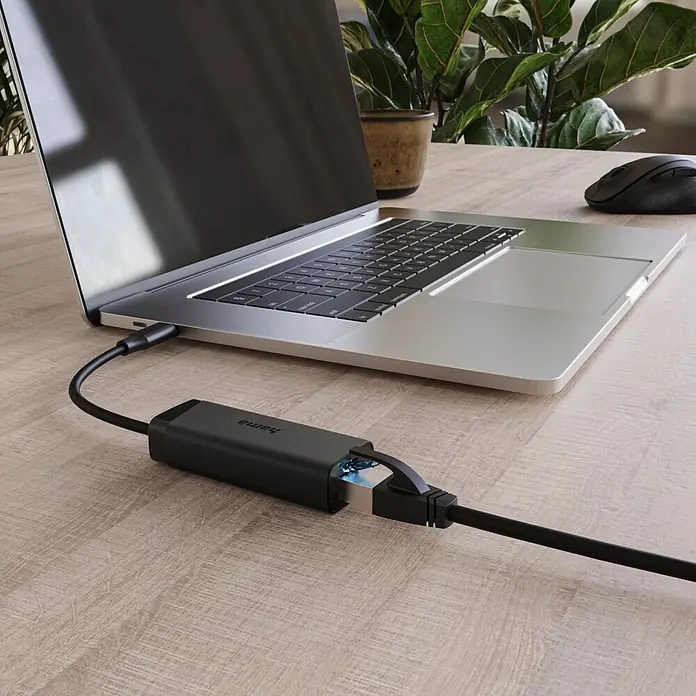 Hama Netzkabel USB 2.0 1x USB-C - 1x RJ45-Buchse - Schwarz - Schwarzer USB-C-auf-Ethernet-Adapter, an Laptop und Ethernetkabel auf einem Holztisch angeschlossen.