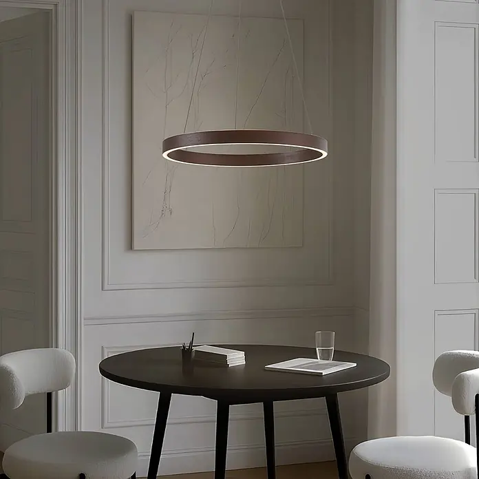 Lucande Pendelleuchte Yonam - braun / rost, kaffeebraun, weiß - Runde LED-Pendelleuchte aus dunklem Holz beleuchtet einen Essbereich mit dunklem Tisch und zwei Stühlen.