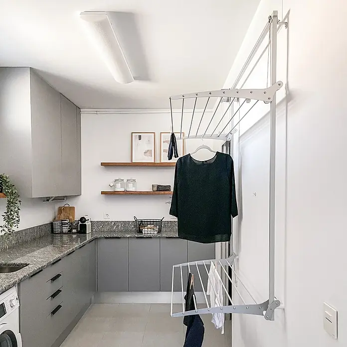 Foxydry Wandwäschetrockner Wall Plus 100 Weiß - 108 cm, Farbe: Weiß - Grauer wandmontierter, verstellbarer Wäschetrockner in einer modernen Waschküche mit aufgehängter Kleidung.