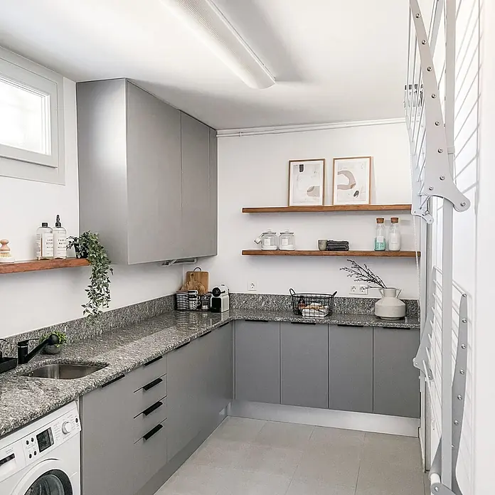Foxydry Wandwäschetrockner Wall Plus 100 Weiß - 108 cm, Farbe: Weiß - Moderner Waschraum mit grauen Schränken, Granitarbeitsplatten, einer Waschmaschine und einem klappbaren Wäscheständer.