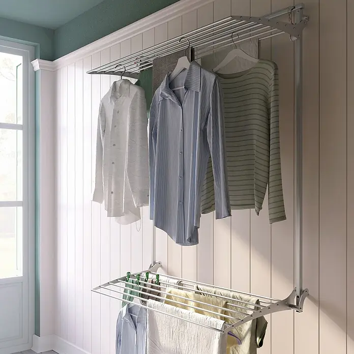 Foxydry Wandwäschetrockner Wall Plus 100 Grau - 108 cm, Farbe: Stahlgrau - Wandmontiertes Wäschetrocknungsgestell mit zwei Ebenen, auf dem in einem hellen Raum verschiedene Kleidungsstücke trocknen.