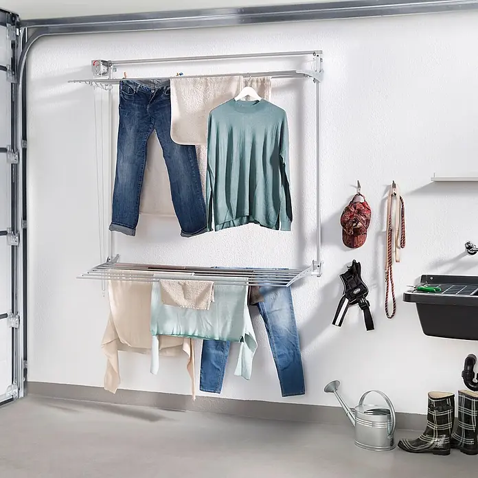 Foxydry Wandwäschetrockner Wall Plus 100 Grau - 108 cm, Farbe: Stahlgrau - Wandmontiertes silbernes Wäschetrocknungssystem mit Wäsche, in einem Hauswirtschaftsraum gezeigt.