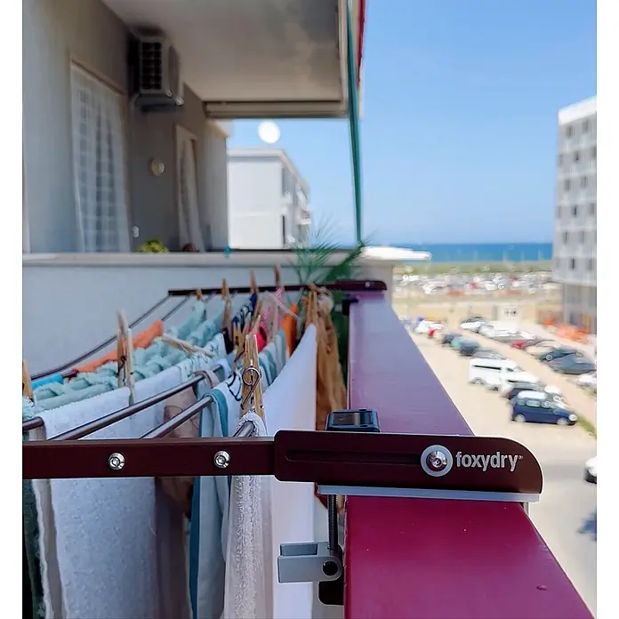 Foxydry Wandwäschetrockner Duo 200 Corten - 202 cm, Farbe: Corten-Optik - Brauner foxydry Wäscheständer an Balkonbrüstung mit Wäsche, Blick auf das Meer.