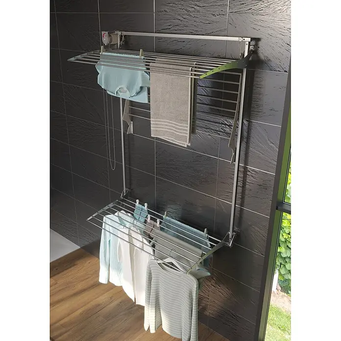 Foxydry Wandwäschetrockner Tower 150 Grau - 150 cm, Farbe: Stahlgrau - Zweistufiger, wandmontierter Wäschetrockner aus Metall mit Kleidung und Handtüchern, vor einer dunklen Fliesenwand.