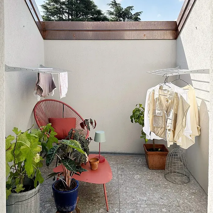 Foxydry Wandwäschetrockner Fold 60 Grau - 62 cm, Farbe: Stahlgrau - Weißer wandmontierter Wäscheständer mit hängender Kleidung, im Freien auf einer Terrasse.