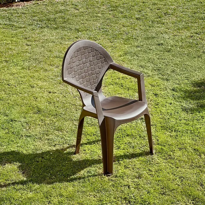 Silla de jardín Dream - 56 x 60 x 87,5 cm, Wengué, Polipropileno, Apilable - Una silla de plástico marrón con reposabrazos sobre una hierba verde. La silla es simple pero robusta, perfecta para sentarse al aire libre.