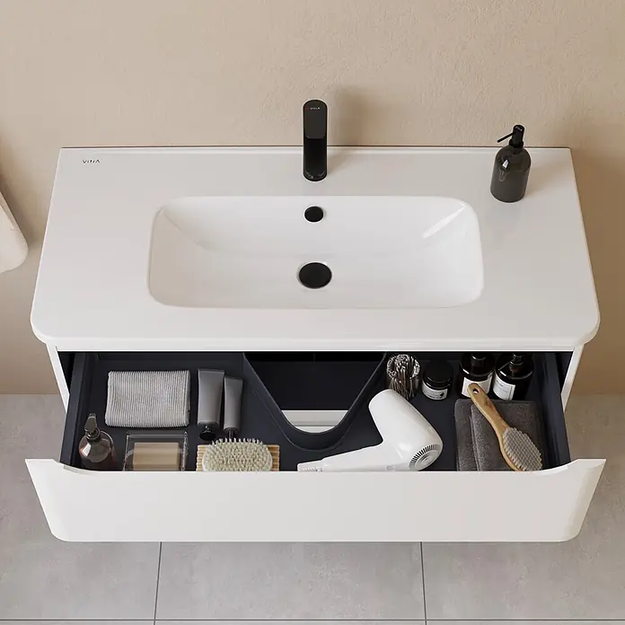 VitrA Integra Round Badmöbel-Set - Gesamtbreite Badmöbel: 100 cm, Weiß, Matt - Weißer Waschtisch mit integriertem Waschbecken, schwarzem Wasserhahn und geöffneter Schublade mit Organizer für Badartikel.