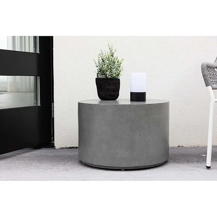 Ebuy24 Garten-Beistelltisch rund Lissabon - Ø x H: 60 x 40 cm, Aluminium, Stapelbar, Grau - Grauer zylindrischer Outdoor-Beistelltisch mit Topfpflanze und moderner Lampe darauf.