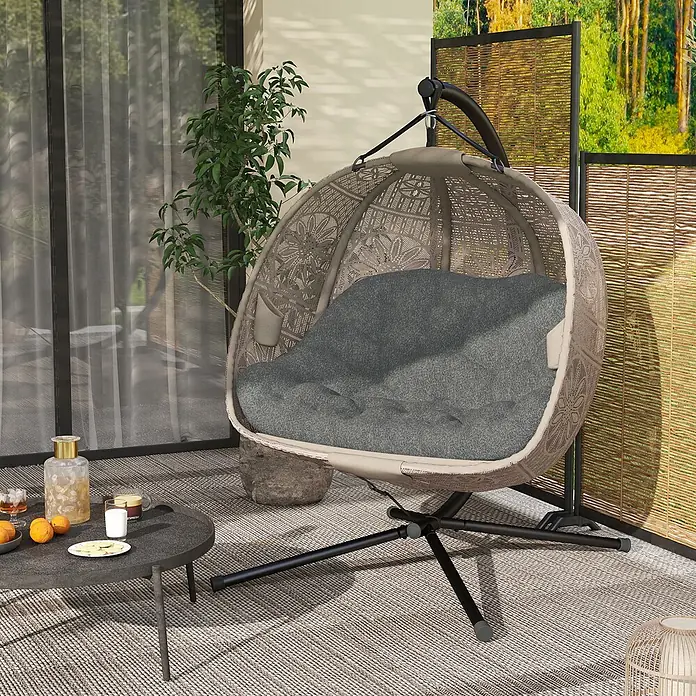 Outsunny Hängesessel - Sand+Schwarz - Beiger Rattan-Hängesessel mit dunkelgrauem Kissen auf schwarzem Stand, ideal für entspannte Stunden auf der Terrasse.
