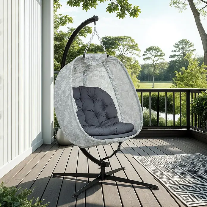 Furnicato Hängesessel - L x B x H: 126 x 90 x 180 cm, Grau - Ein hellgrauer Eier-Hängesessel mit Blattmuster, dunkelgrauem Kissen und schwarzem Gestell, auf einer Holzterrasse.