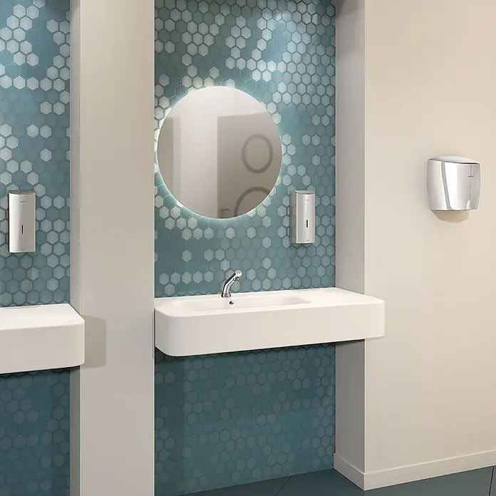 Delabie Spültischarmatur Delabie - Chrom - Moderne Toilette mit weißen Wandseifenspendern und einem silbernen Händetrockner über weißen Waschbecken.