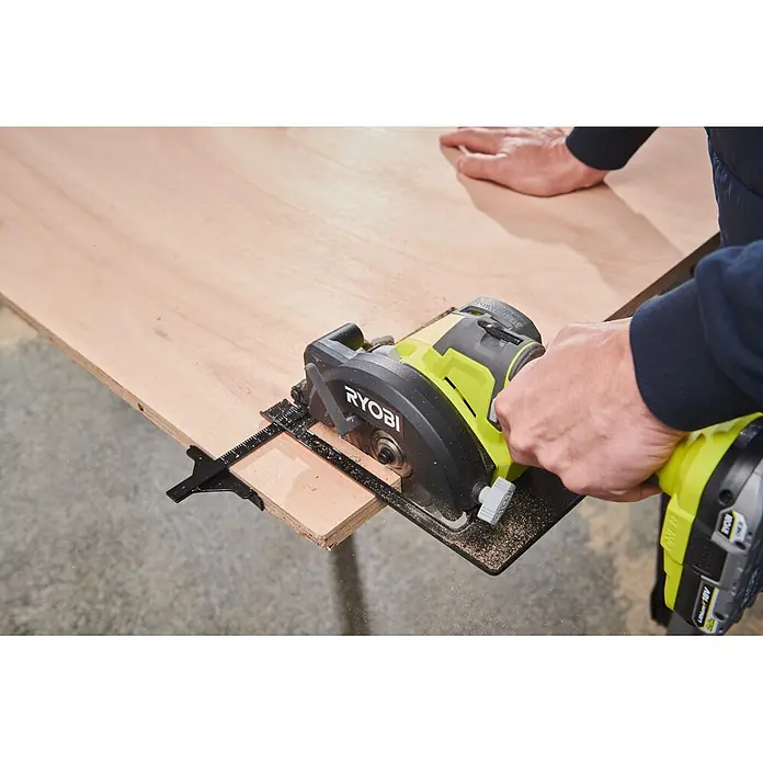 Ryobi ONE+ Akku-Handkreissäge R18CS115 - 18 V, Ohne Akku, Durchmesser Sägeblatt: 115 mm, 5.200 U/min - Ryobi Kreissäge (limettengrün und schwarz) schneidet eine Sperrholzplatte, Sägemehl fliegt.