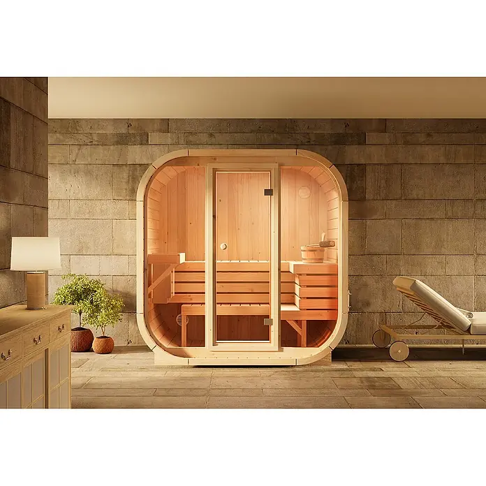 FinnTherm Massivholzsauna Ellipso M -  - Helle Holzfasssauna mit Glastür in einem Spa-Raum, ausgestattet mit Bänken und Eimer.