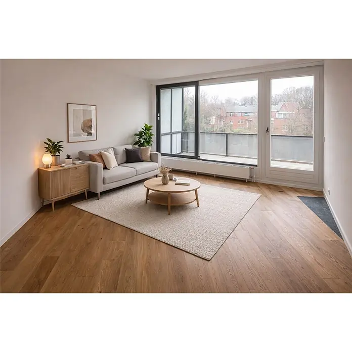 Parkett - Eiche Trier, Landhausdiele, 1.900 x 190 x 14 mm - Hellbeiger, strukturierter rechteckiger Teppich in einem modernen Wohnzimmer, unter einem runden Couchtisch vor einem grauen Sofa.