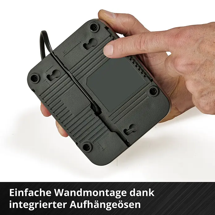 Einhell PXC 18V Akku & Ladegerät PXC-Starter-Kit - 18 V, 1 Akku, 4 Ah - Dunkelgraues Elektronikgerät mit integrierten Aufhängeösen für einfache Wandmontage, von einer Hand gehalten.