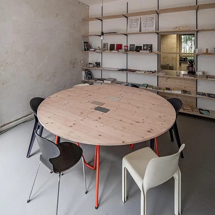 elka 3-Schichtplatte Vita - Douglasie, 2.500 x 660 x 19 mm - Großer runder Holztisch mit orangefarbenen Beinen in einem Besprechungs-/Arbeitszimmer, umgeben von Stühlen.