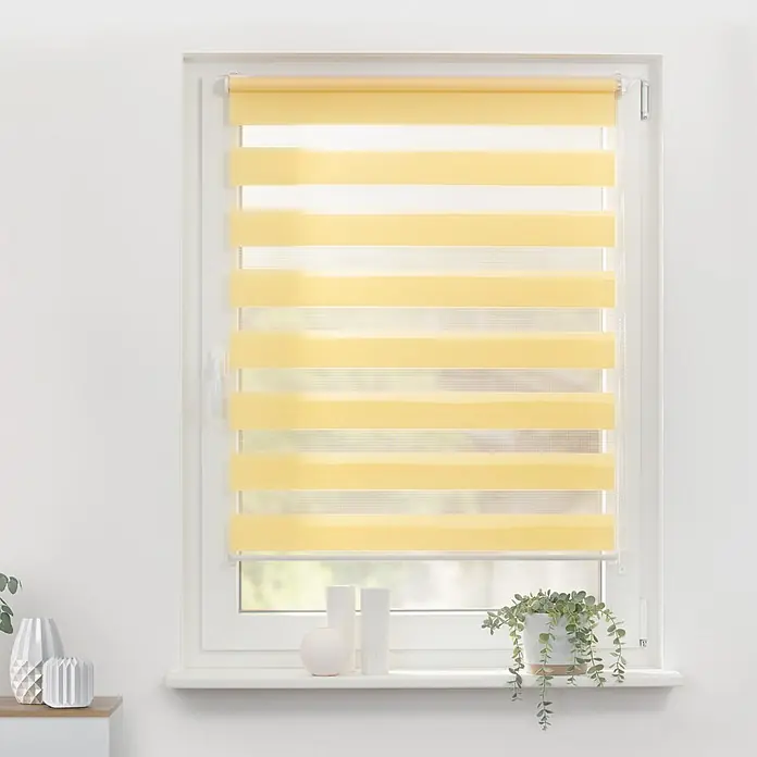 Lichtblick Doppelrollo -  - Gelbe und weiße gestreifte Duo-Rollos in einem hellen Fenster, die abwechselnd transparente und blickdichte Stoffstreifen zeigen.