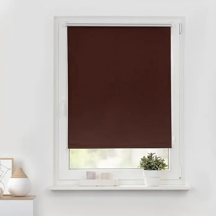 Lichtblick Thermorollo - Braun - Dunkelbraunes Rollo im weißen Fensterrahmen, das Fenster teilweise bedeckend.