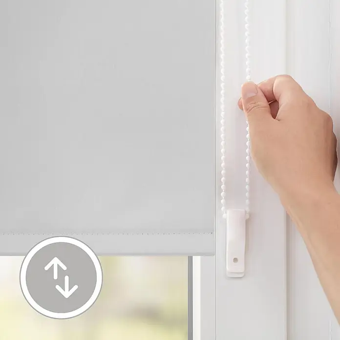 Lichtblick Thermorollo - Weiß - Eine Hand verstellt ein lichtgraues Rollo mit seiner Perlenkette. Der Stoff bedeckt teilweise ein Fenster.