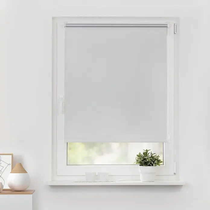 Lichtblick Thermorollo - Weiß - Weißes Rollo, teilweise vor einem Fenster heruntergelassen, zur Lichtregulierung in einem modernen Raum.