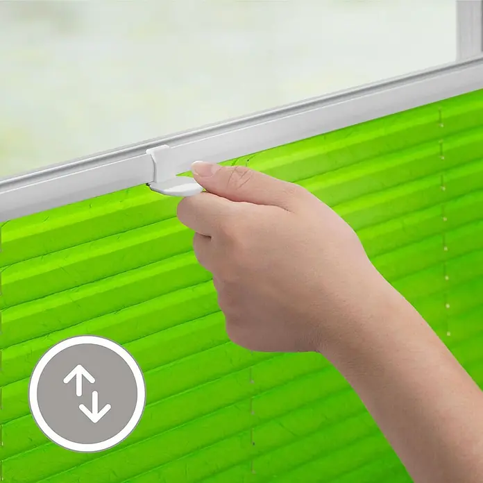 Lichtblick Plissee - Grün - Hand bedient ein leuchtend grünes Plissee am Fenster.