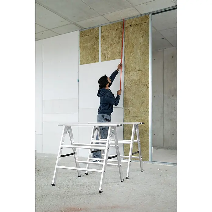 Munk Mehrzweckleiter Aluminium Arbeitsbock, klappbar - Aluminium - Zwei silberne Aluminium-Böcke auf Betonboden in einer Baustellenumgebung.