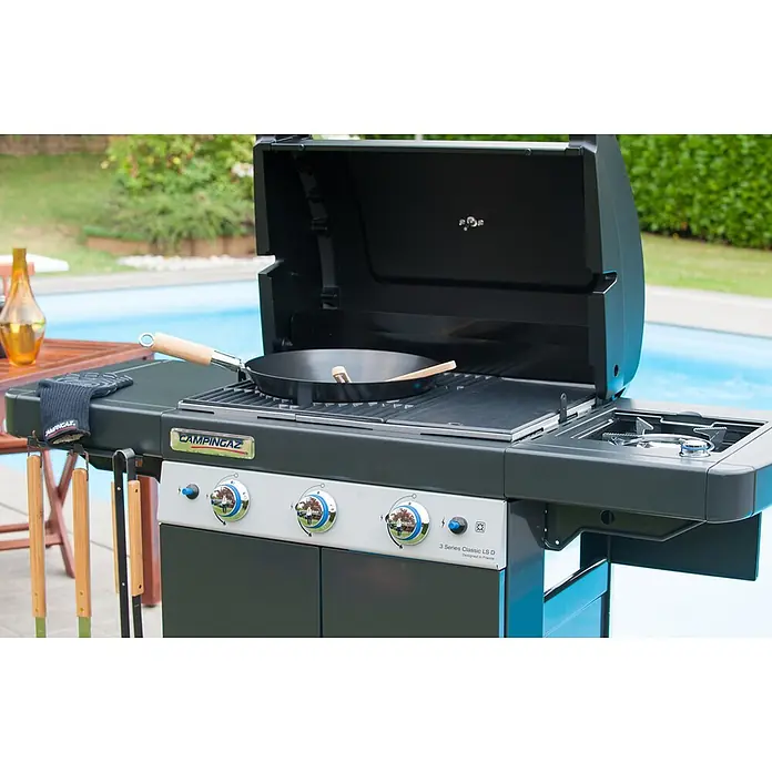 Campingaz Barbacoa de gas Classic LS Plus - Superficie de la parrilla (An x Pr): 61 x 45 cm, 3,2 kW, Número de quemadores: 3 - Parrilla de gas Campingaz gris oscuro con tapa abierta, una sartén en las rejillas y un quemador lateral, lista para cocinar al aire libre.