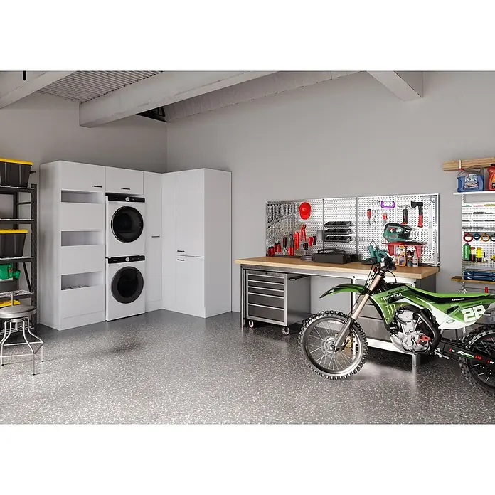 Optifit Optimulti Waschmaschinenschrank Bonn214 - L x B x H: 150 x 213,2 x 210 cm, Weiß - Eine moderne Garage mit weißen Lagerschränken, gestapelter Waschmaschine und Trockner, Werkbank und grünem Dirtbike auf gesprenkeltem Boden.