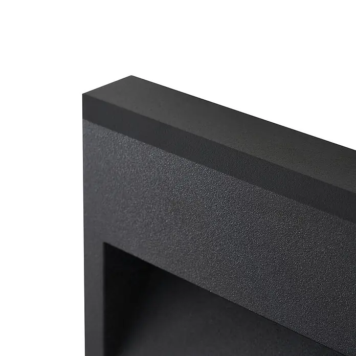 Lucande Außenwandleuchte Weno - 3,5 x 22,7 x 12,7 cm, schwarz, IP65 - Nahaufnahme eines strukturierten, mattschwarzen Rechteckrahmens mit vertiefter Öffnung, deutet auf ein modernes Kamin- oder Heizungsdesign hin.