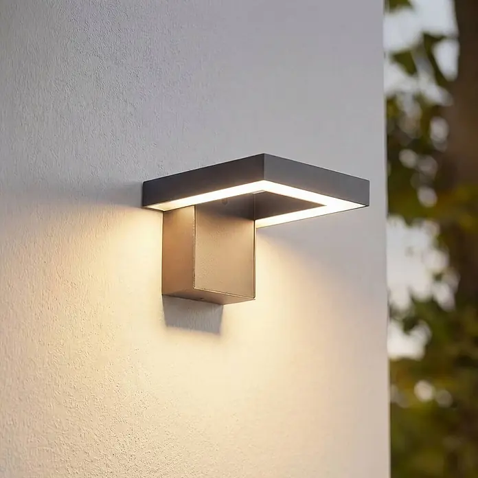 Lindby Außenwandleuchte Orbin - alu / grau / zink, IP54 - Moderne dunkelgraue Außenwandleuchte mit warmem Licht an texturierter Wand.