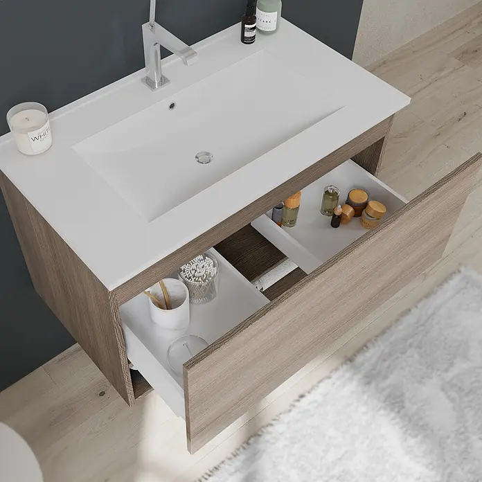 Kiamami Valentina Badmöbel-Set - Holz mittel - Badezimmermöbel mit integriertem weißen Waschbecken und Holzmaserungsschrank. Zwei Schubladen sind geöffnet und zeigen Toilettenartikel.