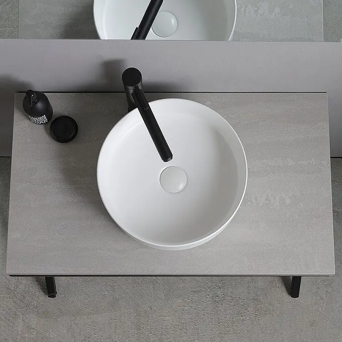 Kiamami Valentina Badmöbel-Set - Wiss, Grau, Schwarz - Rundes weißes Keramikwaschbecken mit matt schwarzem Wasserhahn auf heller grauer Arbeitsplatte, mit schwarzem Seifenspender.