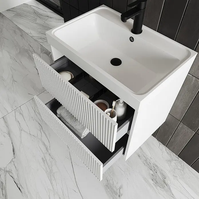 Kiamami Valentina Badmöbel-Set - Weiß - Weißer Badschrank mit integriertem Waschbecken, schwarzem Wasserhahn und zwei offenen gerillten Schubladen für Toilettenartikel.