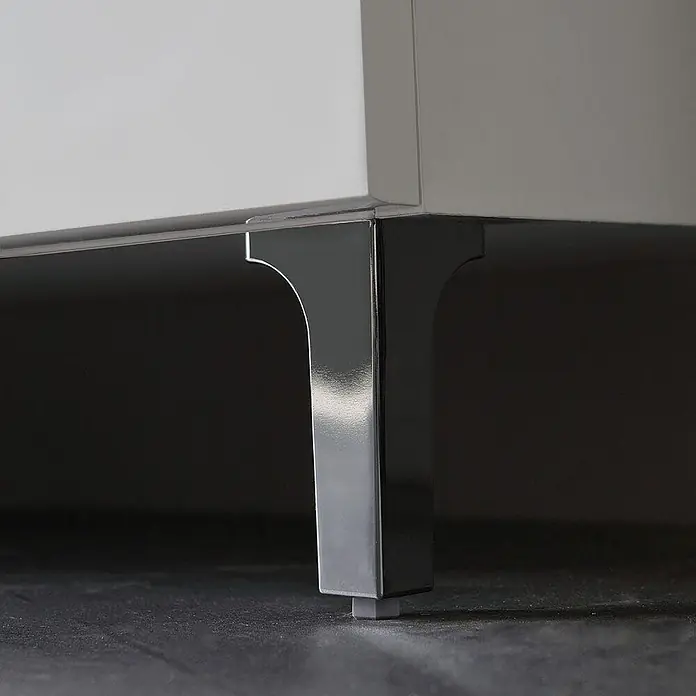 Kiamami Valentina Badmöbel-Set - Weiß - Polierter Chrom-Möbelfuß mit geschwungenem Design, stützt einen weißen Schrank. Mit Schutzunterlage.