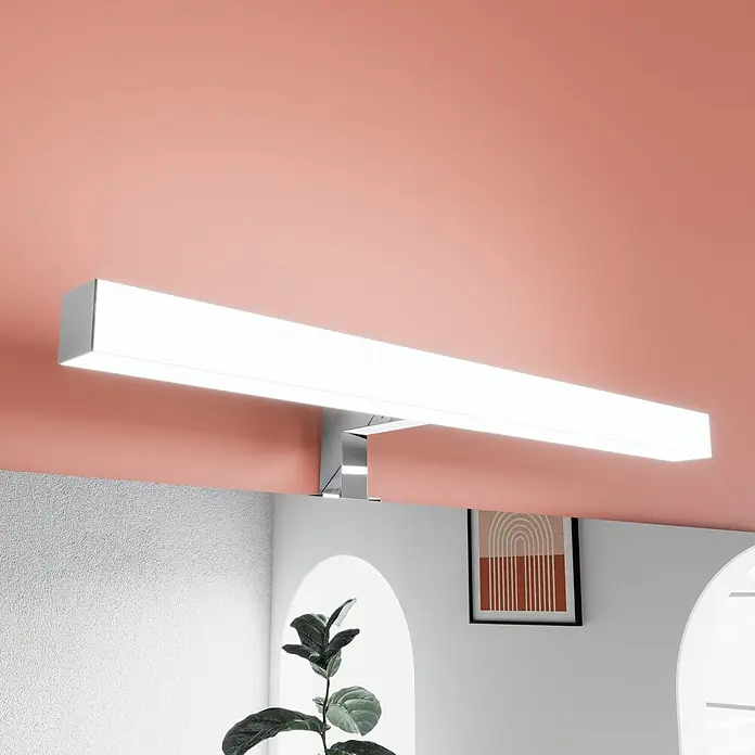 Kiamami Valentina Badmöbel-Set - Schwarz, Grau - Längliche weiße LED-Leuchte an pfirsichfarbener Decke, spendet helles Licht über einem Spiegel.