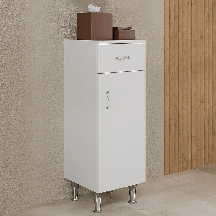 Kiamami Valentina Badmöbel-Set - Weiß - Weißer Hochschrank mit einer Schublade und einer Tür, auf Chrombeinen. Eine Taschentuchbox steht oben.
