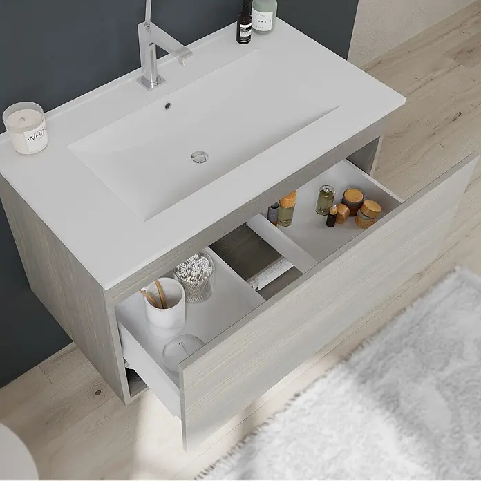 Kiamami Valentina Badmöbel-Set - Helles Holz - Helles, graues Badmöbel in Holzoptik mit weißem Becken und geöffneten Schubladen für Toilettenartikel.