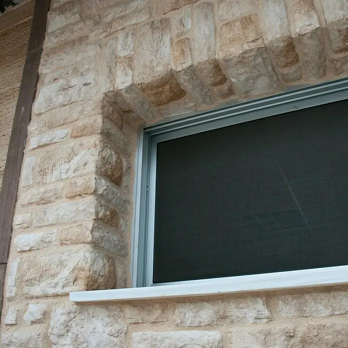 Esquina exterior Silleria Cobre - Cantidad total: 9 pzs. - Primer plano de una ventana con marco de piedra, destacando su encanto rústico y detalles arquitectónicos.