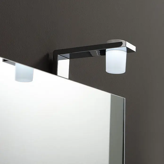 Kiamami Valentina Badmöbel-Set - Weiß - Spiegelleuchte aus Chrom mit zwei satinierten Glasdiffusoren, über einem Spiegel montiert.