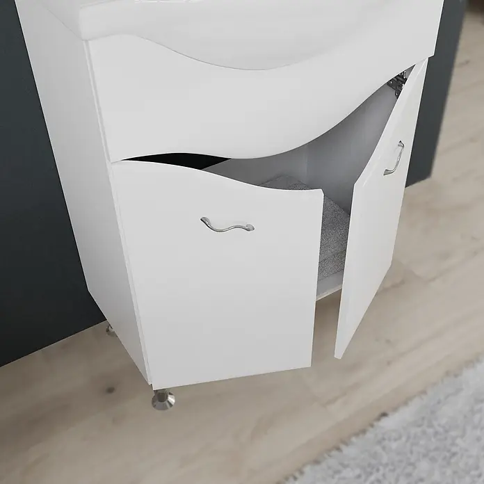 Kiamami Valentina Badmöbel-Set - Weiß - Weißer Badezimmerschrank mit zwei geschwungenen Türen, eine offen mit Handtuch, silbernen Griffen und Beinen.