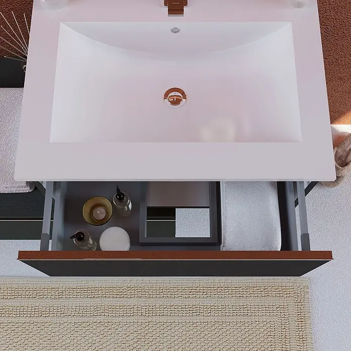 Kiamami Valentina Badmöbel-Set - Grau - Weißer Badschrank mit Rechteckwaschbecken und offener Schublade mit Toilettenartikeln und Handtuch über beigem Badteppich.
